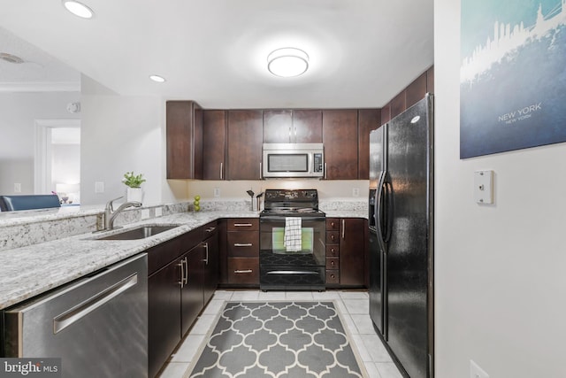 kitchen featuring light tile patterned floors, light stone countertops, dark brown cabinets, black appliances, and a sink