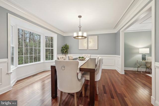 dining room featuring visible vents, an inviting chandelier, ornamental molding, dark wood-type flooring, and a wainscoted wall