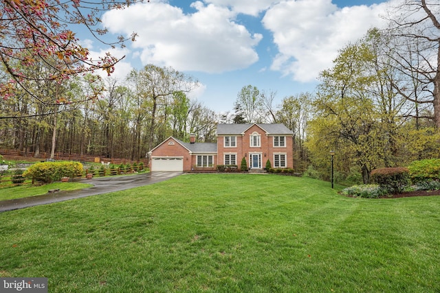 view of front of home featuring brick siding, driveway, a garage, and a front yard