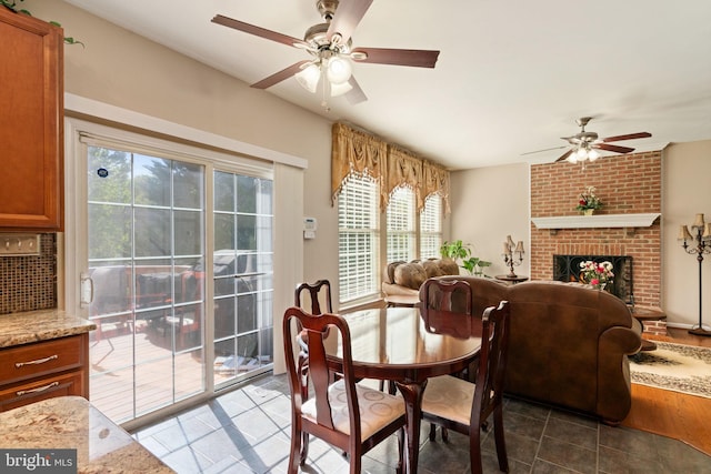 tiled dining space with a fireplace and ceiling fan