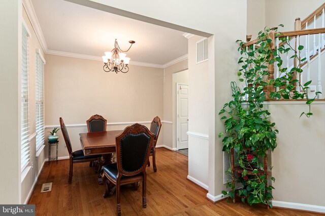 dining room with ornamental molding, wood finished floors, a chandelier, and visible vents