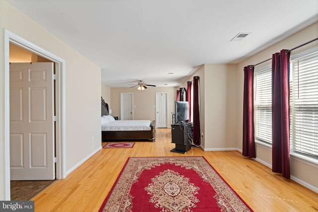 bedroom with baseboards, a ceiling fan, light wood-style floors, and visible vents