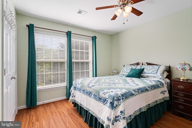 bedroom featuring baseboards, wood finished floors, visible vents, and ceiling fan