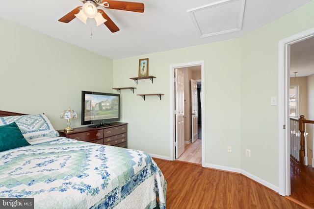 bedroom featuring attic access, wood finished floors, a ceiling fan, and baseboards