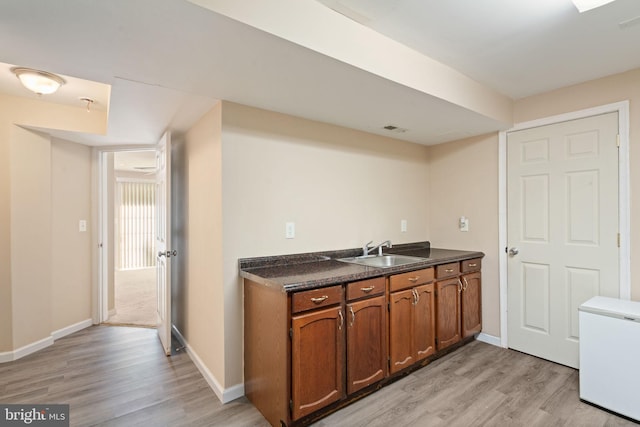 bar with visible vents, a sink, light wood finished floors, and white fridge