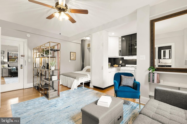 living room with baseboards, ceiling fan, and light wood-style flooring