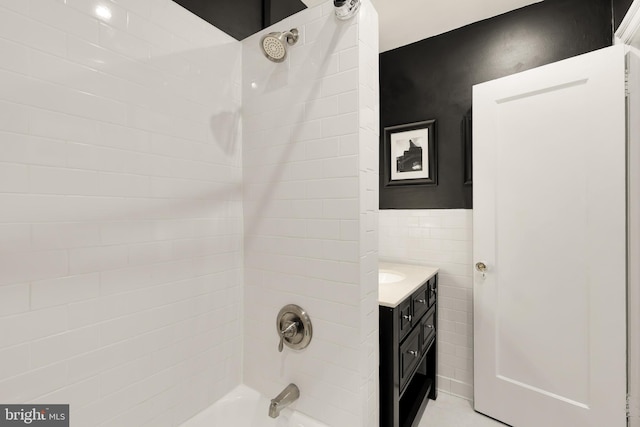 full bath featuring tile walls, washtub / shower combination, and vanity
