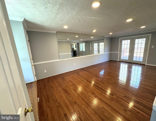 unfurnished living room featuring hardwood / wood-style floors, a textured ceiling, ornamental molding, and french doors
