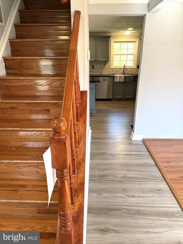 stairs with wood finished floors, visible vents, and baseboards
