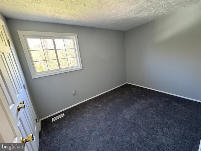 unfurnished room featuring dark carpet, a textured ceiling, baseboards, and visible vents