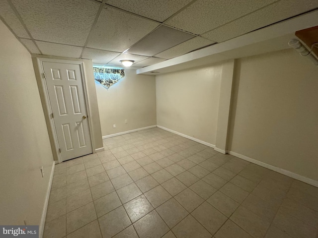 finished below grade area with tile patterned floors, baseboards, and a drop ceiling