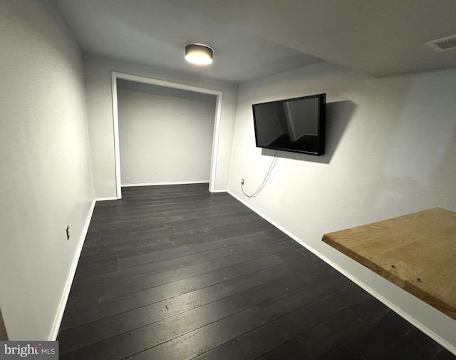 hallway featuring baseboards, dark wood-type flooring, and visible vents