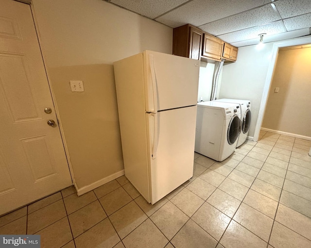 clothes washing area with washing machine and dryer, baseboards, cabinet space, and light tile patterned floors