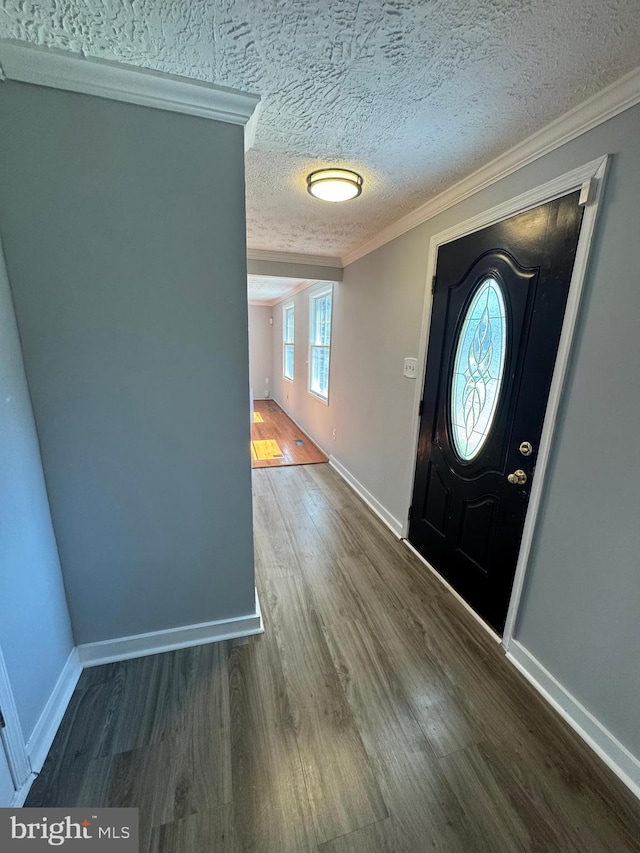 foyer featuring baseboards, wood finished floors, a textured ceiling, and ornamental molding