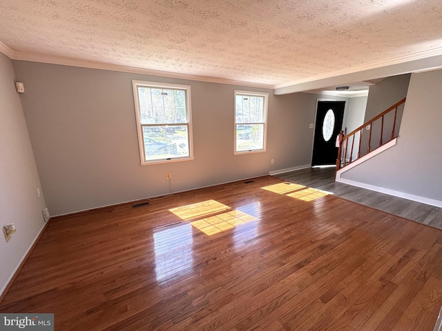 unfurnished living room with dark wood-style flooring, a textured ceiling, and ornamental molding