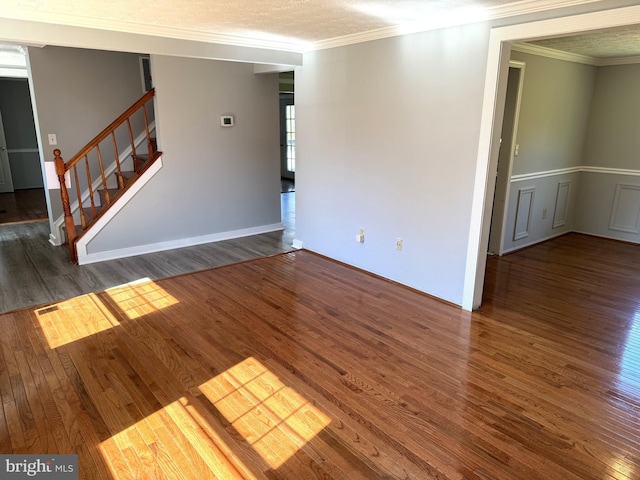 unfurnished living room featuring wood finished floors, crown molding, and stairway