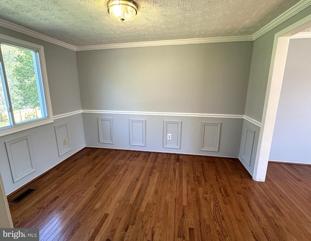 unfurnished room with wood finished floors, a textured ceiling, wainscoting, ornamental molding, and visible vents