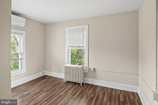 empty room with wood finished floors, a wall mounted air conditioner, baseboards, and radiator