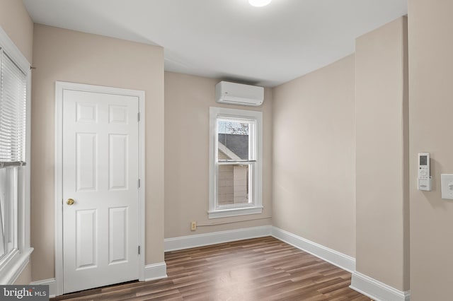 interior space with baseboards, a wall unit AC, and wood finished floors