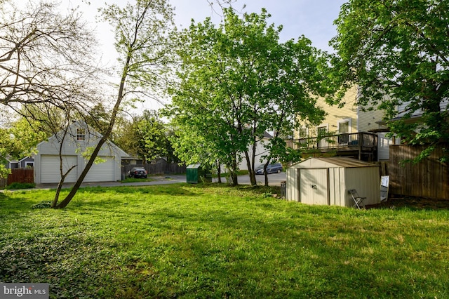 view of yard featuring fence, a storage unit, a detached garage, and an outbuilding