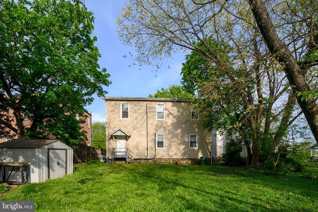 rear view of house with a storage unit, fence, an outbuilding, and a lawn
