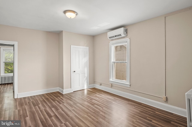 empty room featuring baseboards, radiator heating unit, wood finished floors, and a wall mounted AC