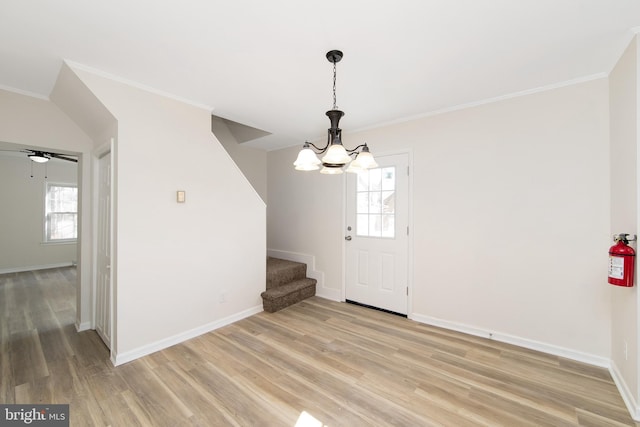 entryway featuring light wood finished floors, a wealth of natural light, crown molding, and a chandelier