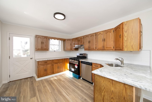kitchen featuring light wood finished floors, brown cabinets, appliances with stainless steel finishes, under cabinet range hood, and a sink