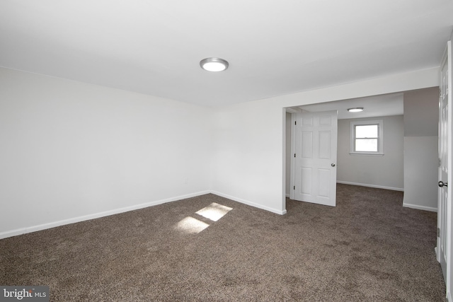 interior space featuring baseboards and dark colored carpet