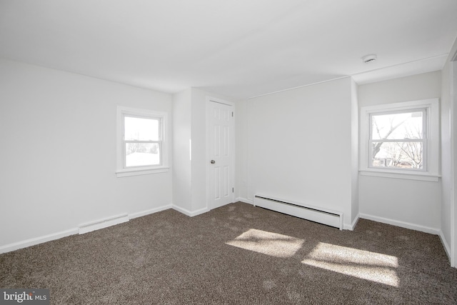 spare room with baseboards, dark colored carpet, and a baseboard heating unit