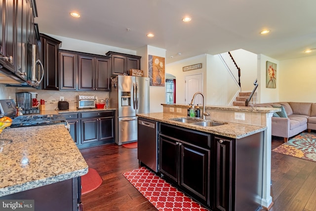 kitchen with stainless steel appliances, a sink, tasteful backsplash, open floor plan, and dark wood-style flooring