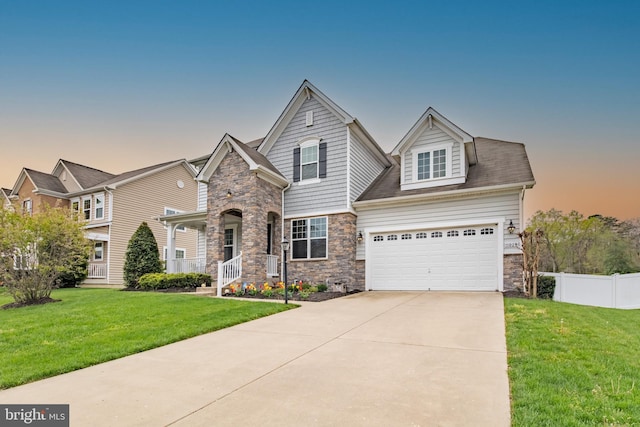 view of front of property with stone siding, driveway, fence, and a yard