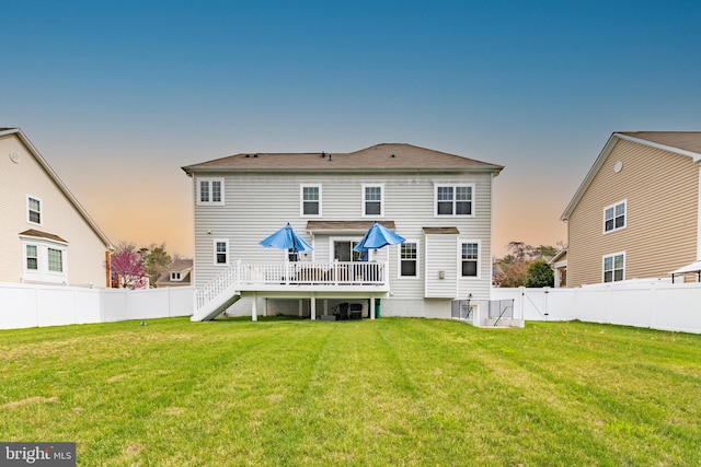 back of house at dusk with stairs, a lawn, a fenced backyard, and a deck