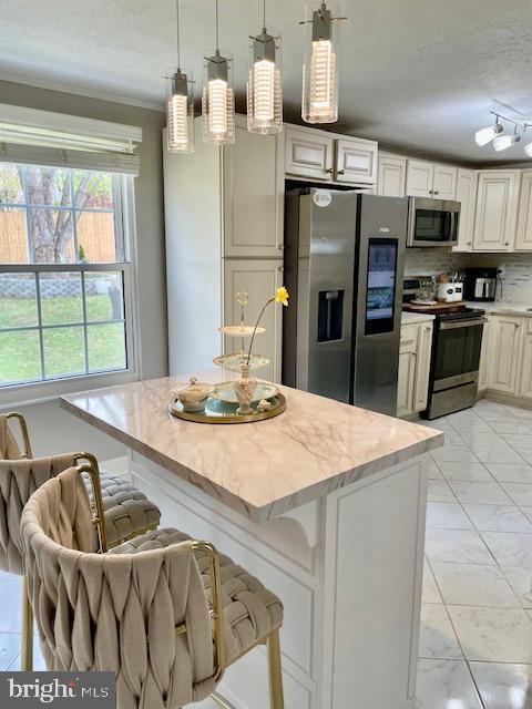 704 Pritchard Ln, Upper Marlboro, MD 20774 - kitchen with a kitchen bar, stainless steel appliances, decorative backsplash, hanging light fixtures, and light stone counters