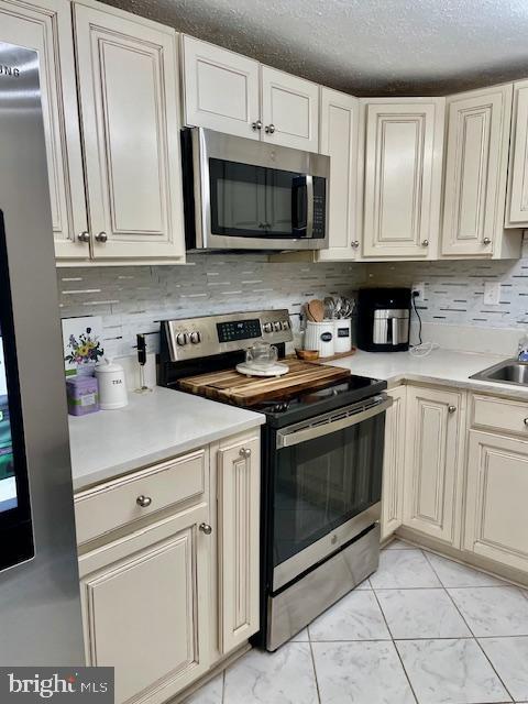 704 Pritchard Ln, Upper Marlboro, MD 20774 - kitchen with a textured ceiling, light countertops, stainless steel appliances, and backsplash