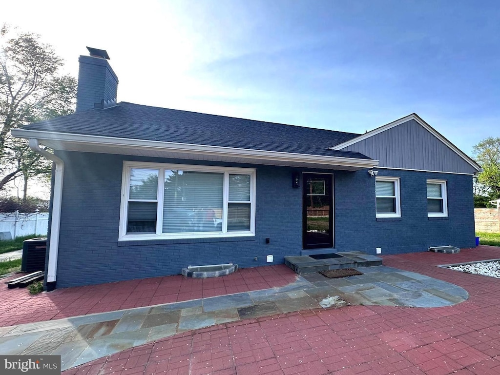14427 Seneca Rd, Germantown, MD 20874 - view of front of house with brick siding, a chimney, central AC, and a patio