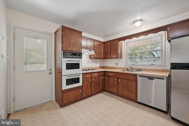 kitchen featuring under cabinet range hood, appliances with stainless steel finishes, a sink, and light countertops