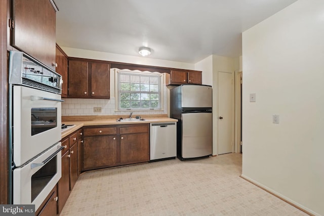 kitchen featuring dark brown cabinetry, backsplash, a sink, light countertops, and stainless steel appliances