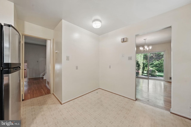 unfurnished room with baseboards, light wood finished floors, and a notable chandelier