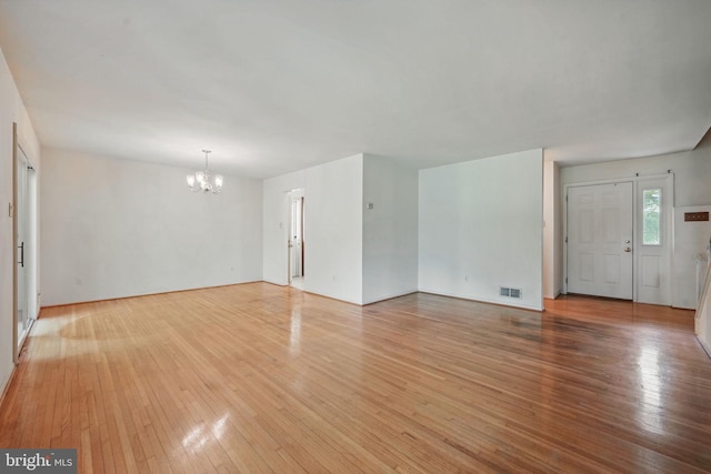 unfurnished living room featuring a chandelier, visible vents, and light wood-type flooring