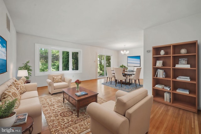 living room featuring an inviting chandelier, wood finished floors, and visible vents