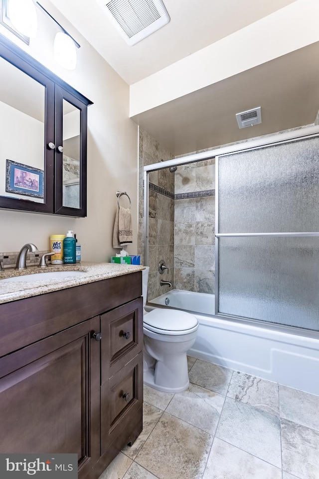 bathroom featuring vanity, toilet, and combined bath / shower with glass door