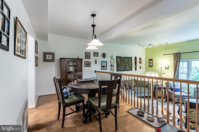 dining space with wood finished floors, track lighting, and baseboards