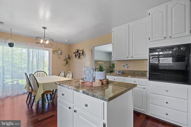 1513 Millikens Bend Rd, Herndon, VA 20170 - kitchen featuring black oven, dark wood-style flooring, a center island, dark stone counters, and white cabinetry