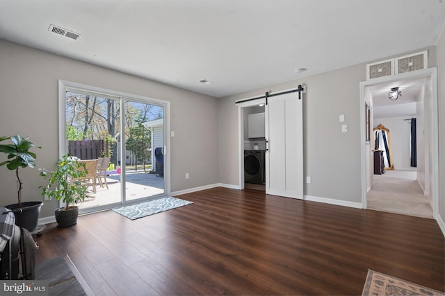 1513 Millikens Bend Rd, Herndon, VA 20170 - unfurnished living room featuring washer / dryer, a barn door, wood finished floors, and baseboards