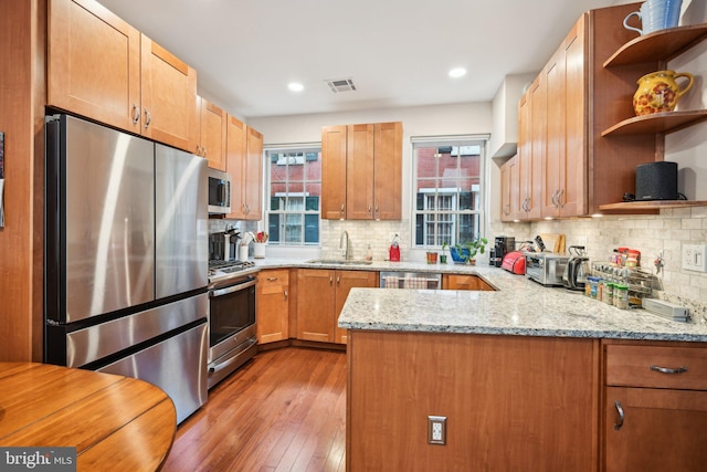 311 S American St, Philadelphia, PA 19106 - kitchen featuring appliances with stainless steel finishes, open shelves, a sink, a peninsula, and light wood-type flooring