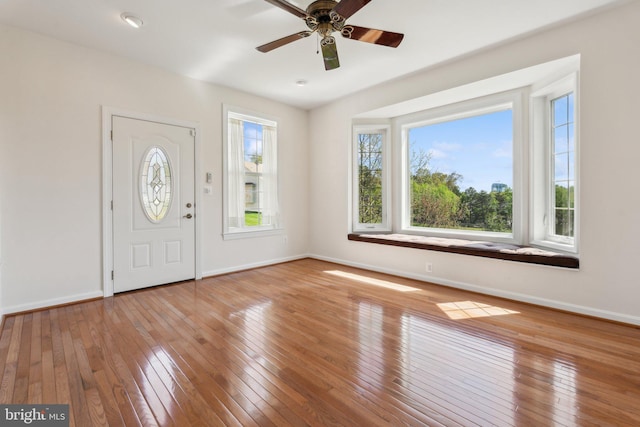 foyer entrance featuring hardwood / wood-style floors, a ceiling fan, and baseboards