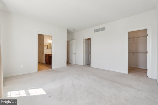 unfurnished bedroom featuring a spacious closet, carpet, visible vents, and baseboards
