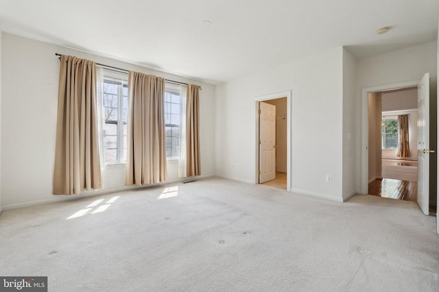unfurnished bedroom with carpet floors, multiple windows, visible vents, and baseboards