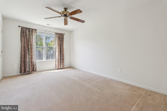 spare room featuring carpet floors, visible vents, a ceiling fan, and baseboards